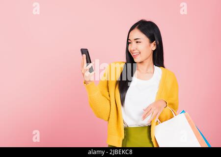 Ritratto Asiatico felice giovane donna teen shopper sorridente in piedi eccitato tenendo online borse shopping online colorato multicolore e smartphon Foto Stock