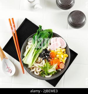 Udon, Noodles giapponesi con vari tipi di verdure Topping, Nori Laver, e seme di Sesamo in ciotola di ceramica. Vista dall'alto Foto Stock