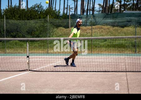 Giocatore di tennis che esegue un tiro di caduta sul campo. Foto Stock