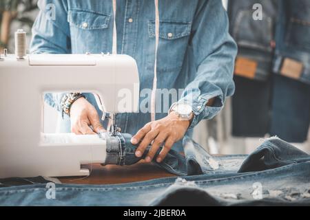 Da lavoro su misura con jeans in denim blu. Personalizza l'orlo dei jeans blu. Foto Stock