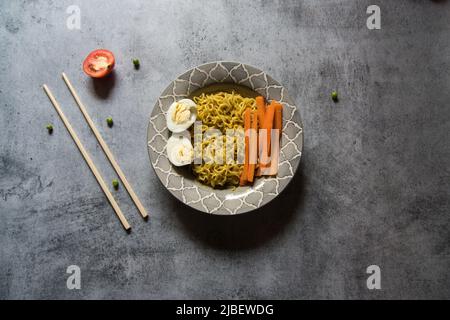 Piatti cotti ramen noodle serviti in una ciotola su sfondo. Primo piano, messa a fuoco selettiva. Foto Stock