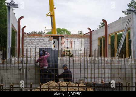 uomo che lavora in cantiere costruzione casa privata e strutture in cemento armato dell'edificio in costruzione. ponteggio. Gru Foto Stock