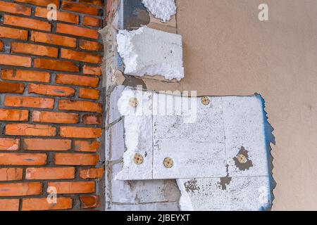 Smantellamento della facciata di una casa privata. Isolamento in polistirene espanso su una parete di blocco di calcestruzzo cellulare sullo sfondo di un wa Foto Stock