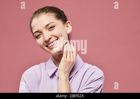 Candid ritratto di donna femminile giovane sorridente alla fotocamera su sfondo rosa vibrante, spazio copia Foto Stock