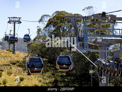 Six gondolas, three going up carrying bikes and passengers and three heading down the mountain at Thredbo in the Snowy Mountains Foto Stock