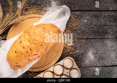 pane baguette con cipolla ripieno cotto in forno su sfondo di legno, farina di grano e uova per la cottura, pane per una deliziosa colazione Foto Stock