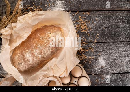 Panetteria. Pane croccante rustico dorato su sfondo di legno nero. Vista del pane dall'alto, posa piatta. Spazio copia Foto Stock