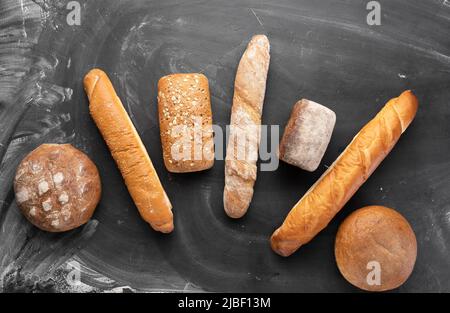 Pane fresco su sfondo nero, vista dall'alto. Dolci fatti in casa freschi di vari pani di grano e segale da vicino. Foto Stock