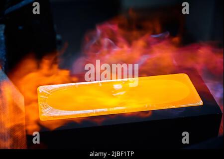 Il lingotto d'oro caldo si briviglia in forma di fusione nei gas di protezione Foto Stock