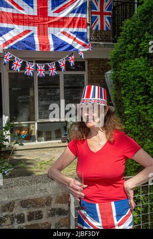 Donna di fronte a Union Jack bandiere e coniglietti fuori da una casa del consiglio a Londra per celebrare i 70 anni del regno di sua Maestà la Regina. Foto Stock