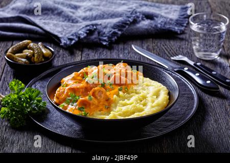 nakkikastike, salsicce in salsa di pomodoro cremosa con purè di patate in ciotola nera, cucina finlandese, vista orizzontale dall'alto Foto Stock