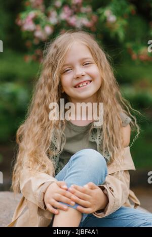 Ritratto di una felice sorridente ragazza toothy di sette anni con lunghi capelli marroni Foto Stock