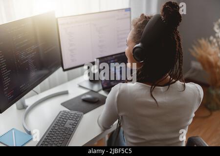 Vista posteriore di una giovane donna professionista che lavora da casa seduto alla scrivania Foto Stock