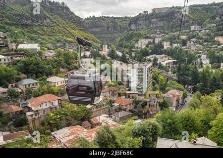 Funivia che passa accanto agli edifici dell'epoca sovietica nella città dei minatori di Chiatura in Georgia Foto Stock