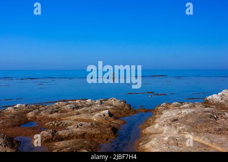 Vista panoramica del mare di Sicilia dove un uomo anziano pesca con bastoni Foto Stock