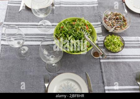 Sfondo estivo, banner. Tavolo da picnic con una grande ciotola di insalata di giardino e piatti Foto Stock