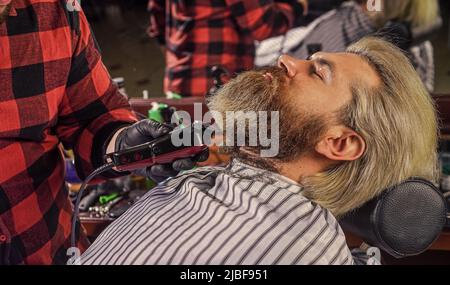 Capelli del viso. Mantenere la forma della barba. Fate crescere la barba e i baffi. Parrucchiere. Uomo al barbiere. Barbiere professionale e cliente. Barbiere è Foto Stock