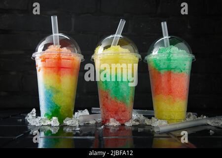 Assortimento di vari drink di slush in fila su sfondo nero e scuro. Foto Stock