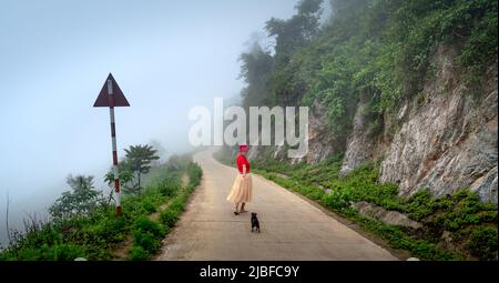 Hang Kia comune, mai Chau Distretto, Provincia di Hoa Binh - 8 maggio 2022: Una turista femminile si sente eccitato mentre cammina su una strada forestale nebbia in Hang Kia Foto Stock