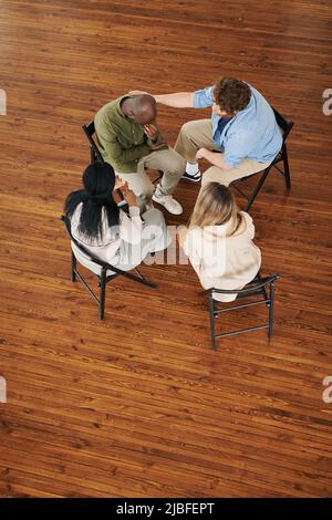 Sopra la vista delle persone interrazziali che sostengono l'uomo afro-americano durante la sessione mentre frequentano il corso di riabilitazione psicologica Foto Stock