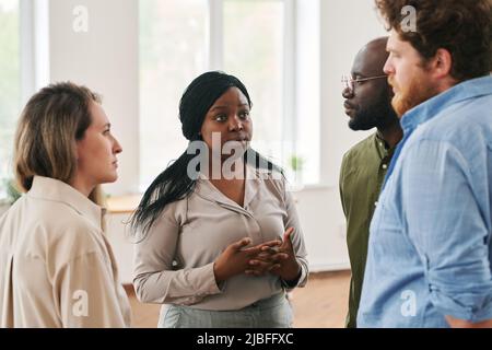 Giovane preoccupata ragazza afroamericana guardando l'uomo caucasico, mentre condividevano i suoi problemi e l'ansia durante la sessione psicologica Foto Stock