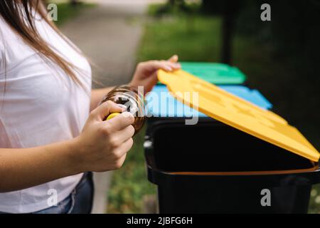 Primo piano ritratto donna lancio a mano vuota bottiglia d'acqua di plastica in contenitore di riciclaggio Foto Stock