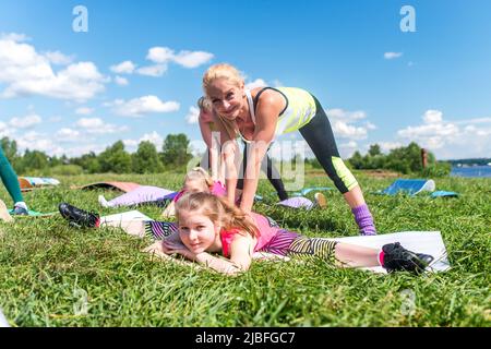 Madre e figlia che fanno l'esercizio di stretching. Formazione di gruppo all'aperto Foto Stock