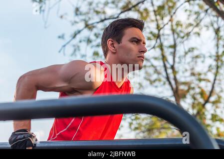 Fit uomo che fa tricipiti tuffa su barre parallele al parco che si esercita all'aperto. Foto Stock