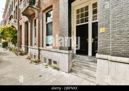 Frammento esterno di moderno edificio residenziale in mattoni situato su strada lastricata in giorno di sole Foto Stock