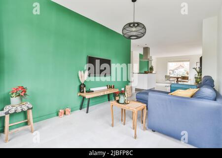 Comodo divano blu posto su tappeto contro la parete con TV e camino in  appartamento luminoso ed elegante con una porta aperta che conduce alla  cucina luminosa Foto stock - Alamy