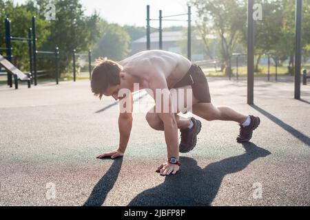 Giovane atleta maschile che fa arrampicate in montagna esercizi di allenamento all'esterno del parco. Foto Stock
