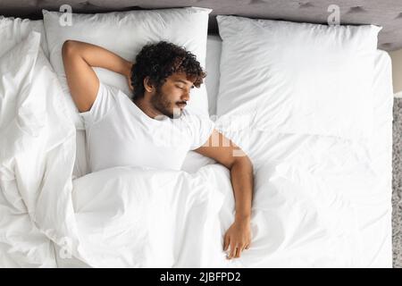 Vista dall'alto di un ragazzo indiano che dorme da solo a letto Foto Stock