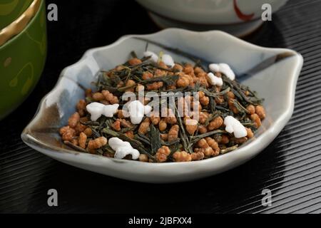 Ciotola con Genmaicha, tè giapponese, tè verde combinato con riso bruno arrostito, alcuni chicchi di cui sono apparsi da vicino Foto Stock