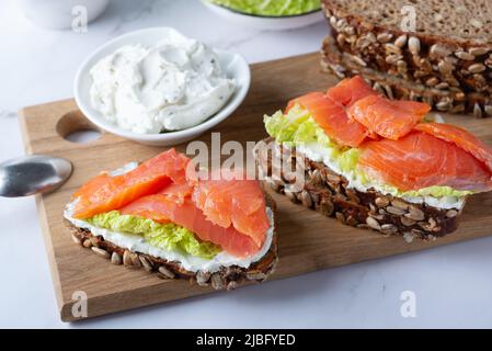 Toast sani con pane di segale con formaggio cremoso, salmone e insalata Foto Stock