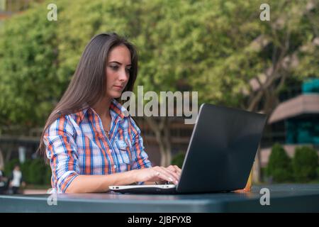 Primo piano di una digitazione femminile con le mani su una tastiera di un laptop. Foto Stock