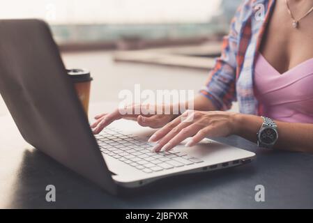 Primo piano di una digitazione femminile con le mani su una tastiera di un laptop. Foto Stock