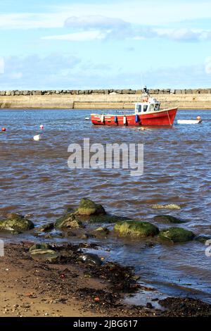 Una piccola barca da pesca nel villaggio di pescatori di Staithes, Yorkshire - una scena moderna simile a quella che ha ispirato il Gruppo di artisti Staithes Foto Stock