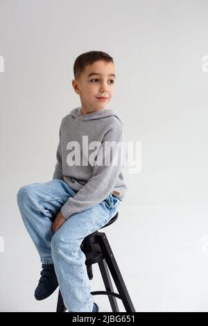 Ragazzo bambino preschooler sorridente e posato su sfondo grigio in studio fotografico Foto Stock