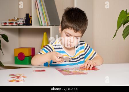 Un preschooler suona puzzle, mette insieme un'immagine Foto Stock