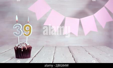 Numero di compleanno. Sfondo festivo per una ragazza o una donna con un muffin e candele che bruciano rosa in colori pastello con decorazioni per qualsiasi vacanza, Foto Stock