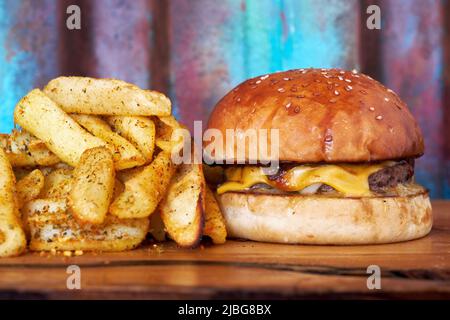 Un hamburger, hamburger o cheeseburger su un piatto di legno con patatine fritte. Foto Stock