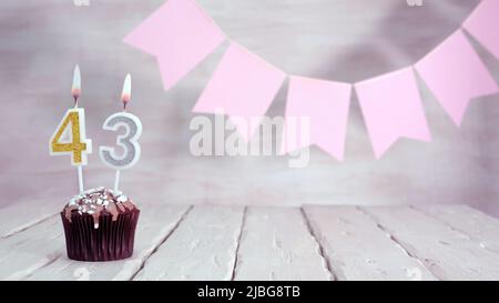 Numero di compleanno. Sfondo festivo per una ragazza o una donna con un muffin e candele che bruciano rosa in colori pastello con decorazioni per qualsiasi vacanza, Foto Stock