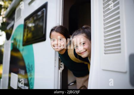 Felice due bambine che guardano fuori dalla caravan e sorridono alla macchina fotografica. Foto Stock