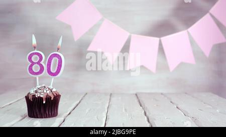 Numero di compleanno. Sfondo festivo per una ragazza o una donna con un muffin e candele che bruciano rosa in colori pastello con decorazioni per qualsiasi vacanza, Foto Stock