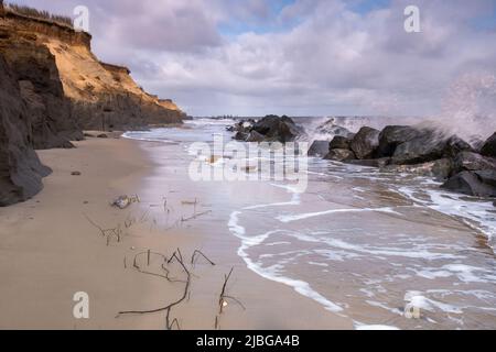 Onde che si infrangono sulle difese marine a Happisburgh sulla costa del Norfolk Foto Stock