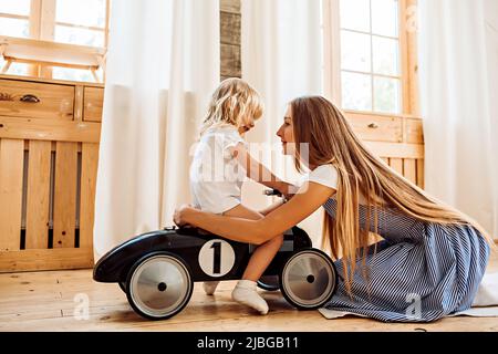 Una giovane madre abbraccia la figlia mentre gioca a casa. Immagine dello stile di vita per il tempo libero della famiglia Foto Stock