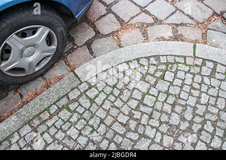 L'immagine del pavimento in pietra ad arco e auto parcheggiata sulla strada a Berlino, Germania Foto Stock