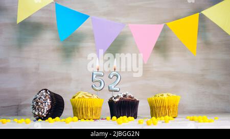 Sfondo compleanno con numero. Bella carta di compleanno con ghirlande colorate, un muffin con una candela che brucia copyspace. Foto Stock