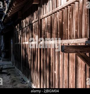 Il primo piano delle pareti esterne in legno della vecchia casa giapponese all'ombra dalla vista laterale nelle giornate di sole. Foto Stock