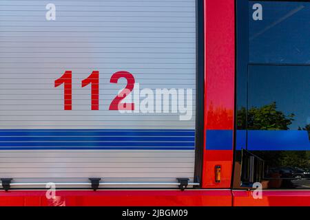 Sportello della serranda per camion antincendio su un motore antincendio tedesco con il numero di telefono di emergenza europeo 112 stampato Foto Stock